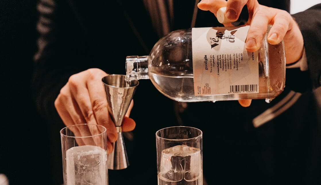 Pouring Về Để Đi spirit into a jigger