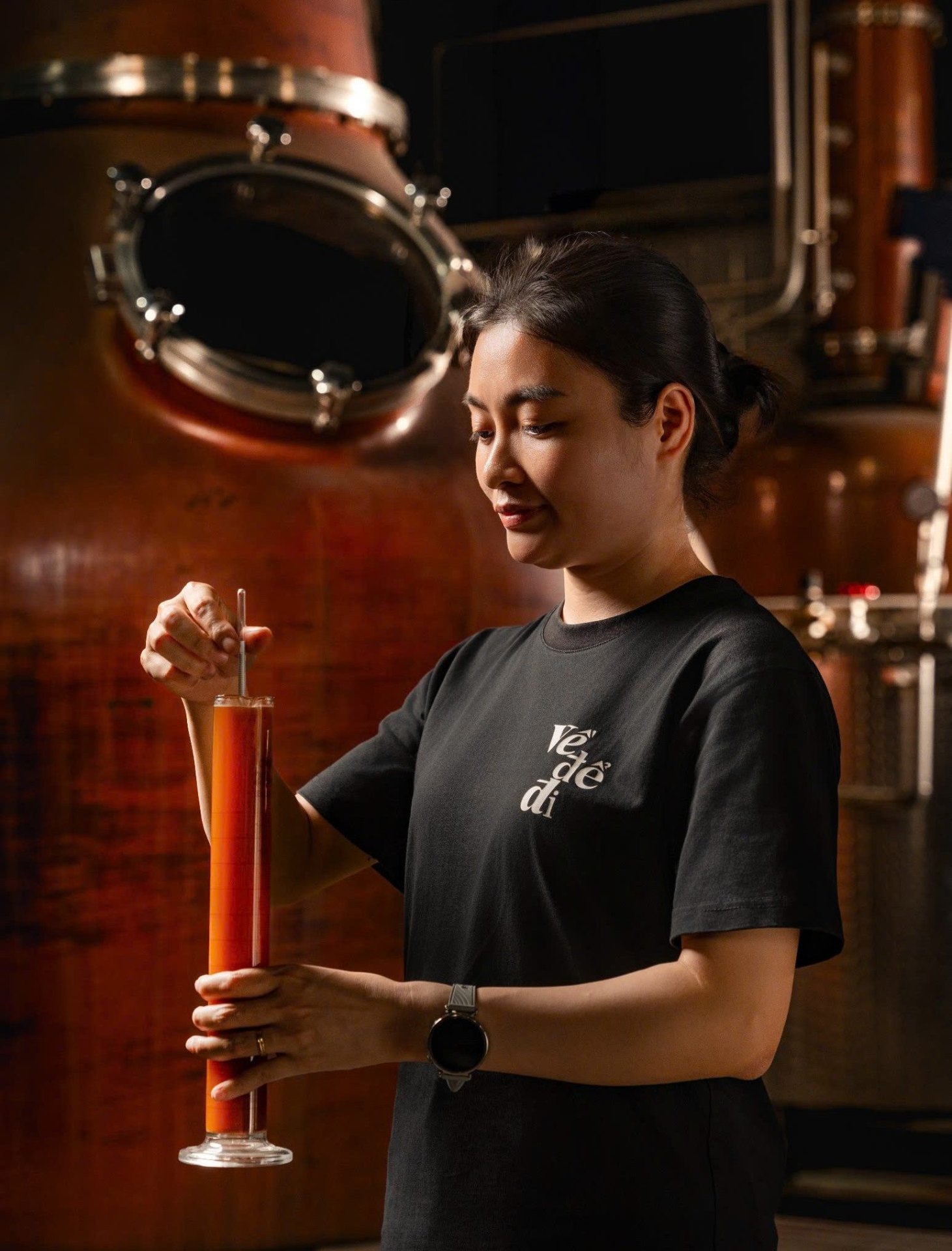 Distiller measuring spirit at the Về Để Đi still in Hanoi